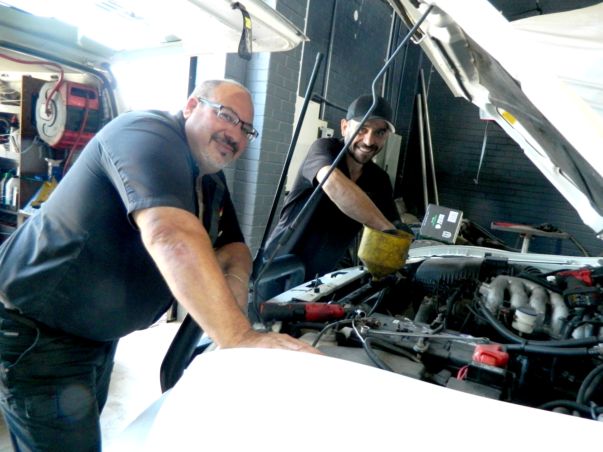 Two mechanics working on vehicle